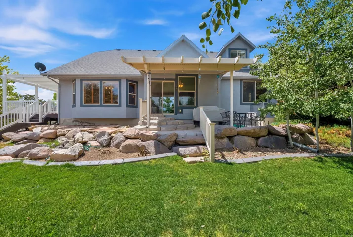 Expansive green lawn with a tiered rock garden leading to a stone patio