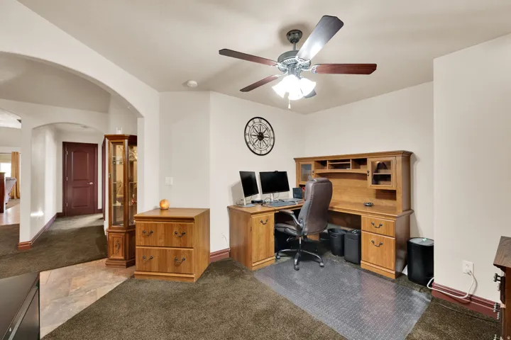 Dedicated space featuring a ceiling fan with integrated lighting, neutral wall tones, and varied flooring with brown carpeting and tile accents