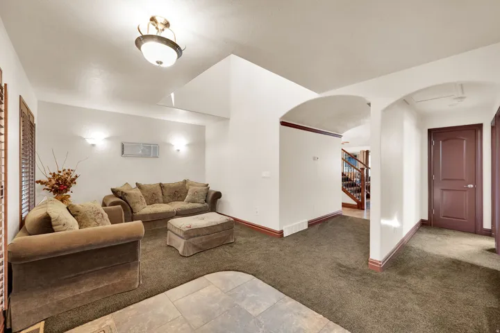 Living area featuring carpet flooring, decorative archways, and dark trim details