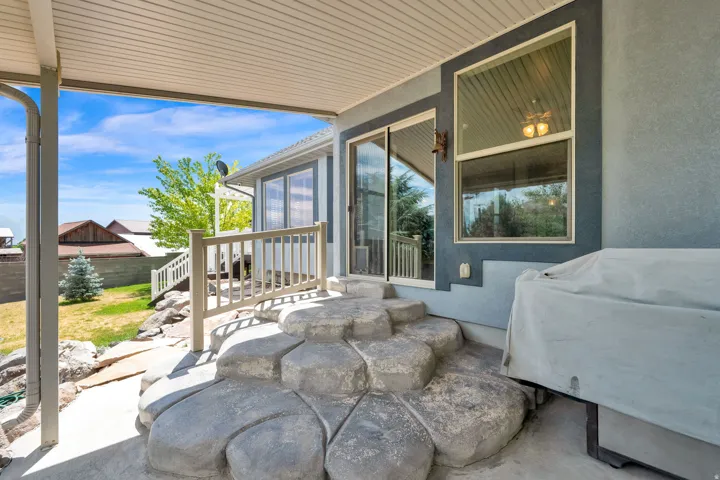 Covered patio featuring a unique stone-look concrete staircase, a light-toned railing, and direct access to interior spaces via a sliding glass door