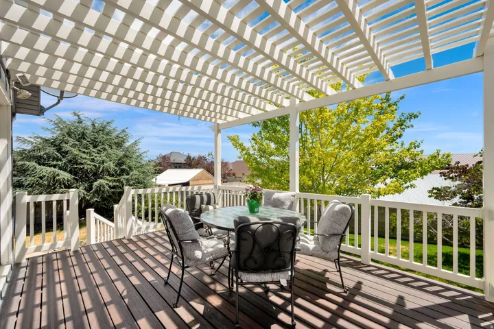 Expansive outdoor deck featuring wood-finish flooring, a white pergola, and white railing