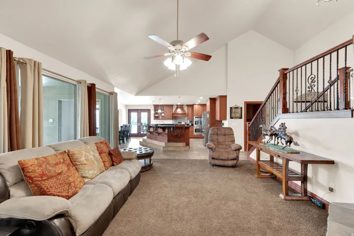 Vaulted ceilings crown this expansive living area featuring carpet flooring