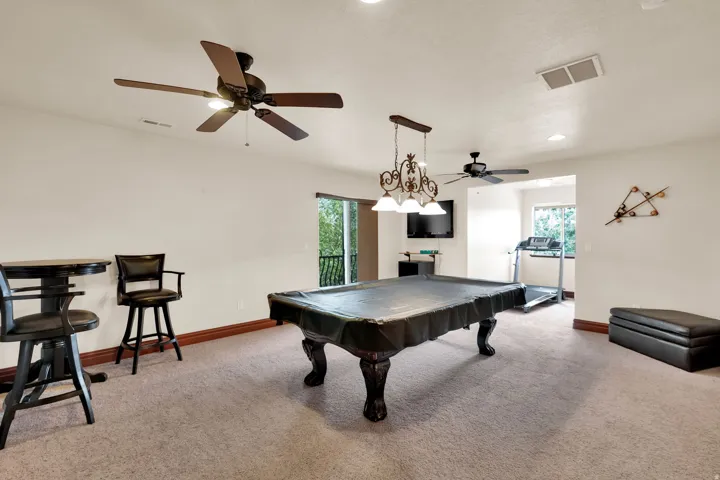 Spacious recreation room featuring neutral carpeting, white walls, and dark wood trim