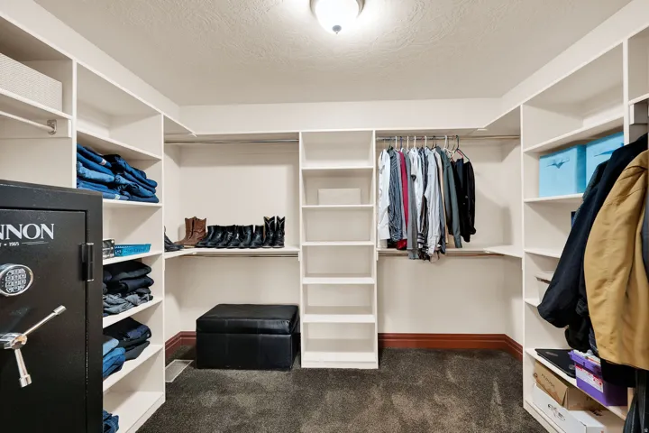 Custom closet organization system featuring white shelving, hanging rods, and dark carpet flooring