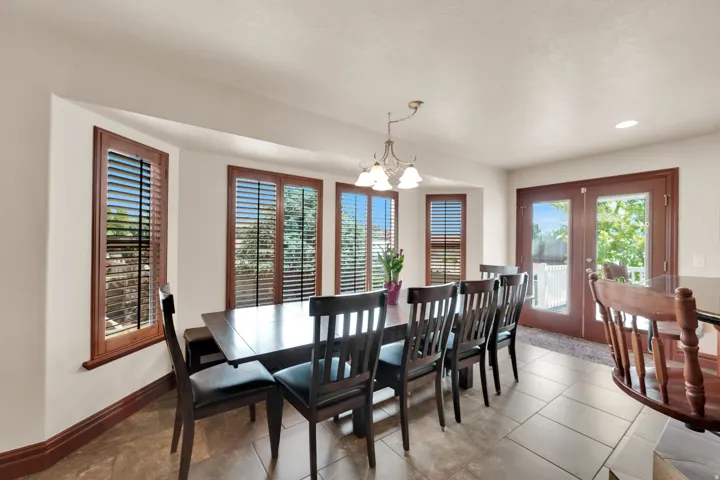 Dining area featuring a bay window with plantation shutters, tile flooring, and a glass-paneled double door