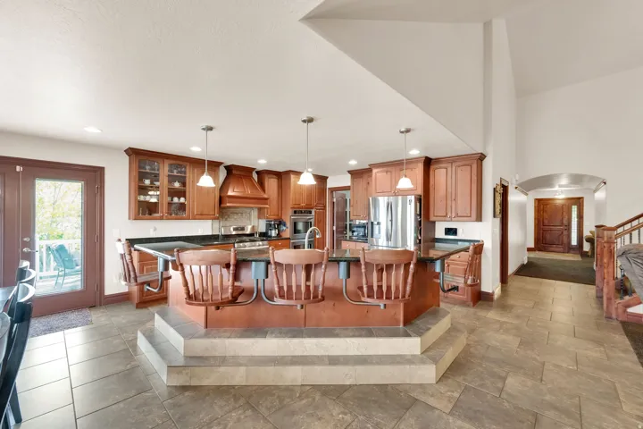 Kitchen featuring a tiered island with seating, pendant lighting, stainless steel appliances, and wood cabinetry