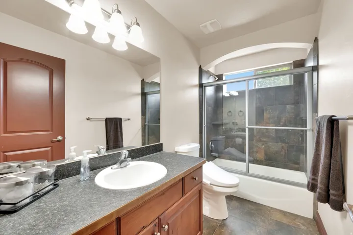 Bathroom featuring a vanity with a white oval sink, a stone-finish countertop, and a wood-finish base cabinetry