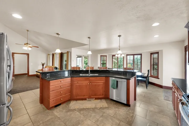 Kitchen featuring a curved island with integrated sink, stainless steel dishwasher, and pendant lighting