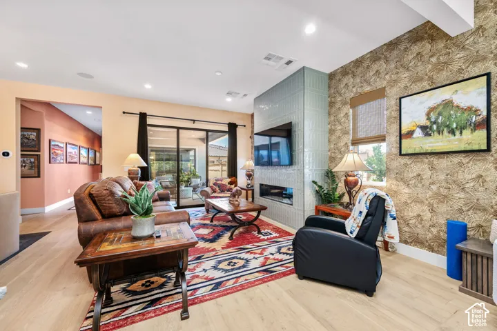 Spacious living area featuring light wood-finish flooring, a tiled fireplace wall with integrated media, and a wall of glass sliding doors