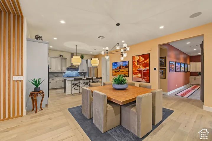 Light wood-finish flooring throughout, recessed ceiling lighting, and a contemporary multi-light chandelier