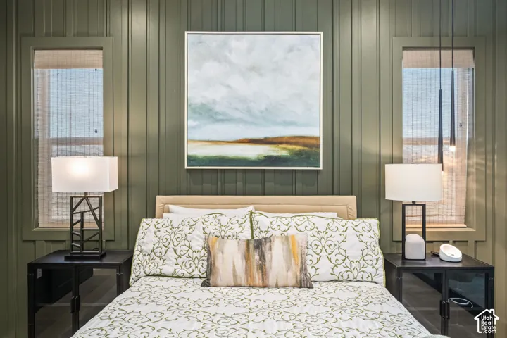 Board and batten wall treatment, symmetrical window placement, integrated window shades, built-in bedside tables, and a neutral upholstered headboard