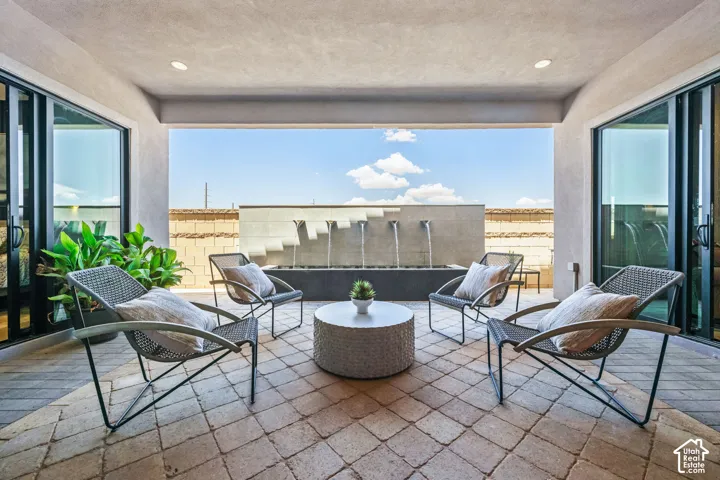 Covered patio with paver flooring, built-in water feature, and dual sliding glass doors