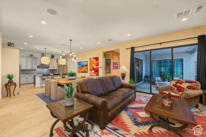 Open-concept living space with light wood-finish flooring, recessed lighting, and a multi-panel sliding glass door