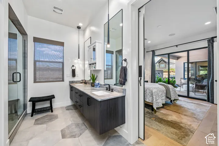 Floating dual vanity with stone countertop, large rectangular mirrors, walk-in shower with glass enclosure, and hexagonal tile flooring