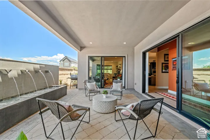 Covered outdoor patio featuring a patterned paver surface, built-in water feature, and dual sliding glass doors