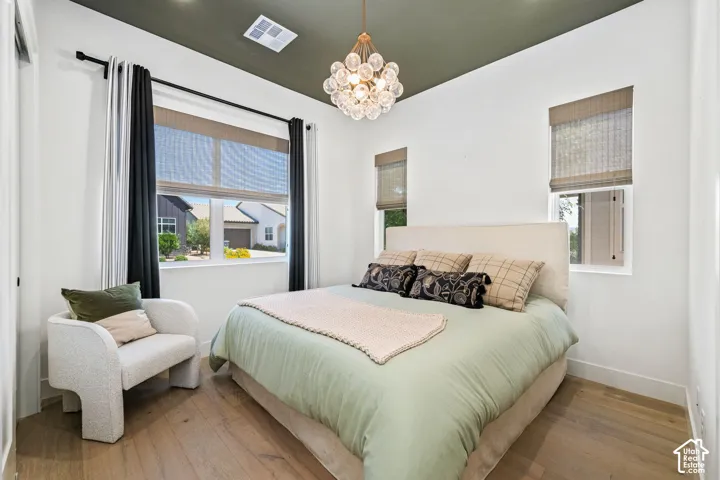 Hardwood-finish flooring, accent ceiling, modern chandelier, multiple windows, window treatments