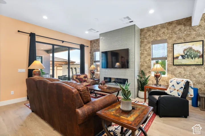Living space featuring light wood-finish flooring and a contemporary fireplace with a vertical tile surround