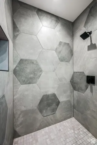 Walk-in shower featuring large hexagonal wall tiles and a matte black showerhead