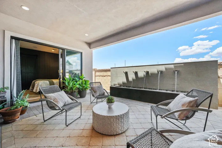 Covered outdoor patio with a built-in water feature, paver flooring, and recessed lighting