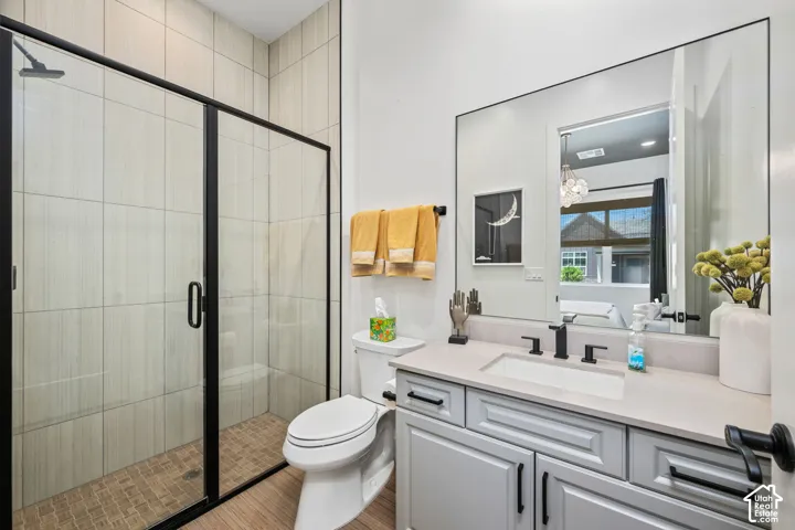 Glass-enclosed shower with a rainfall showerhead, full-height tile surround, and mosaic tile flooring