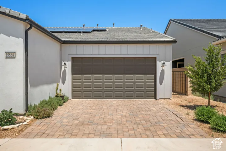 Paver driveway with an attached two-car garage featuring a paneled door