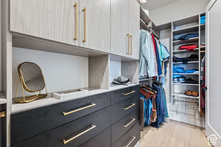 Custom closet system featuring light wood-finish cabinetry, black wood-finish drawers, gold-tone hardware, integrated shelving, and hanging rods