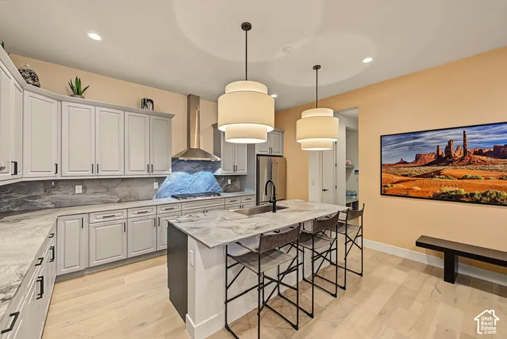 Light wood-finish flooring, light gray cabinetry with black hardware, stainless steel appliances, and a kitchen island with seating