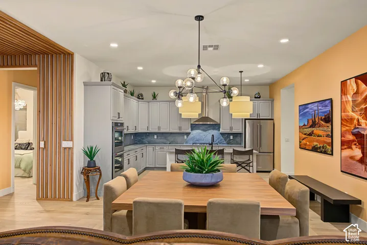 Open-concept living space featuring wood-finish flooring, a contemporary dining chandelier, and recessed lighting
