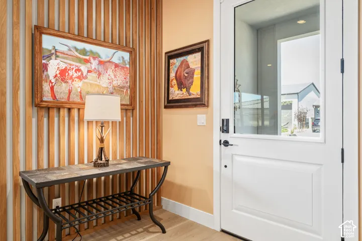 Entryway featuring vertical wood slat accent wall, light wood-finish flooring, and a white paneled door with clear glass insert