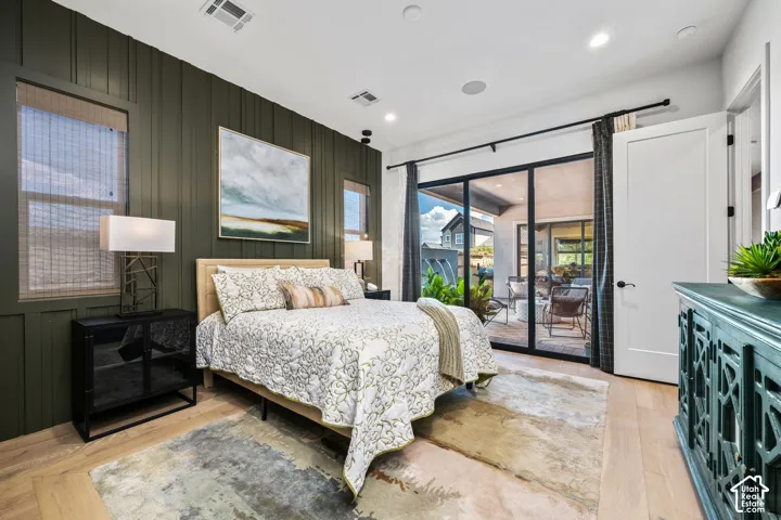 Vertical panel accent wall, recessed lighting, wood-finish flooring, black-framed sliding glass doors, white interior door with black hardware