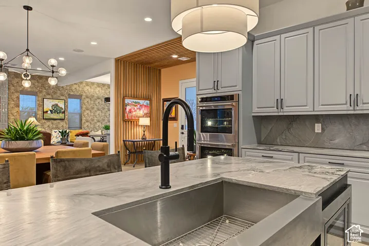 Spacious kitchen with a large basin sink, dark hardware, light cabinetry, and built-in stainless steel appliances