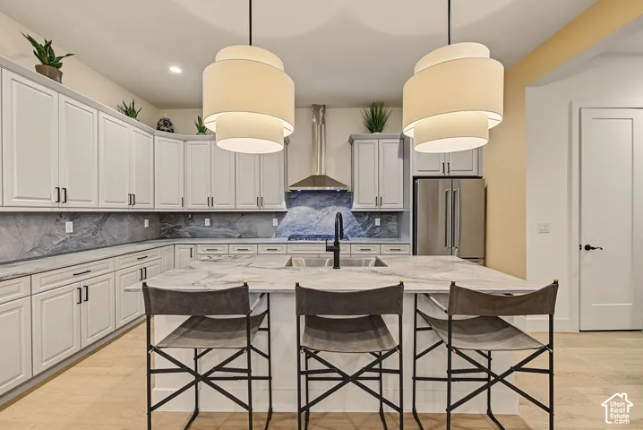 Spacious kitchen featuring an expansive island with a built-in sink, stainless steel appliances, extensive cabinetry, and decorative pendant lighting
