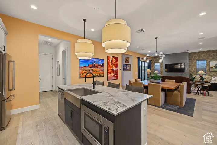 Spacious kitchen island with an undermount farmhouse sink and integrated microwave, wood-finish flooring, and pendant lighting