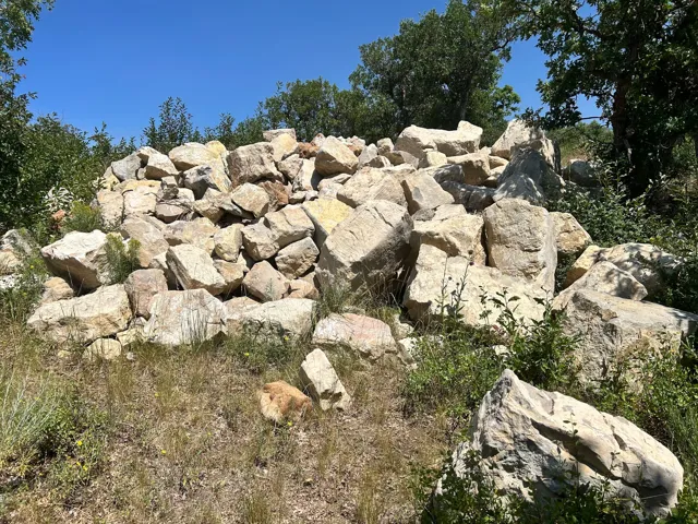 Natural stone rock formation with surrounding vegetation and clear sky