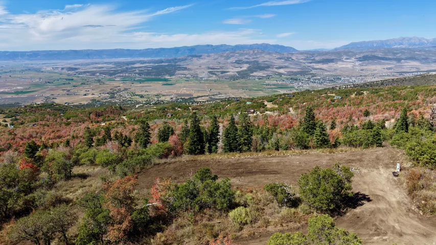 Cleared building site with surrounding foliage and distant mountain range