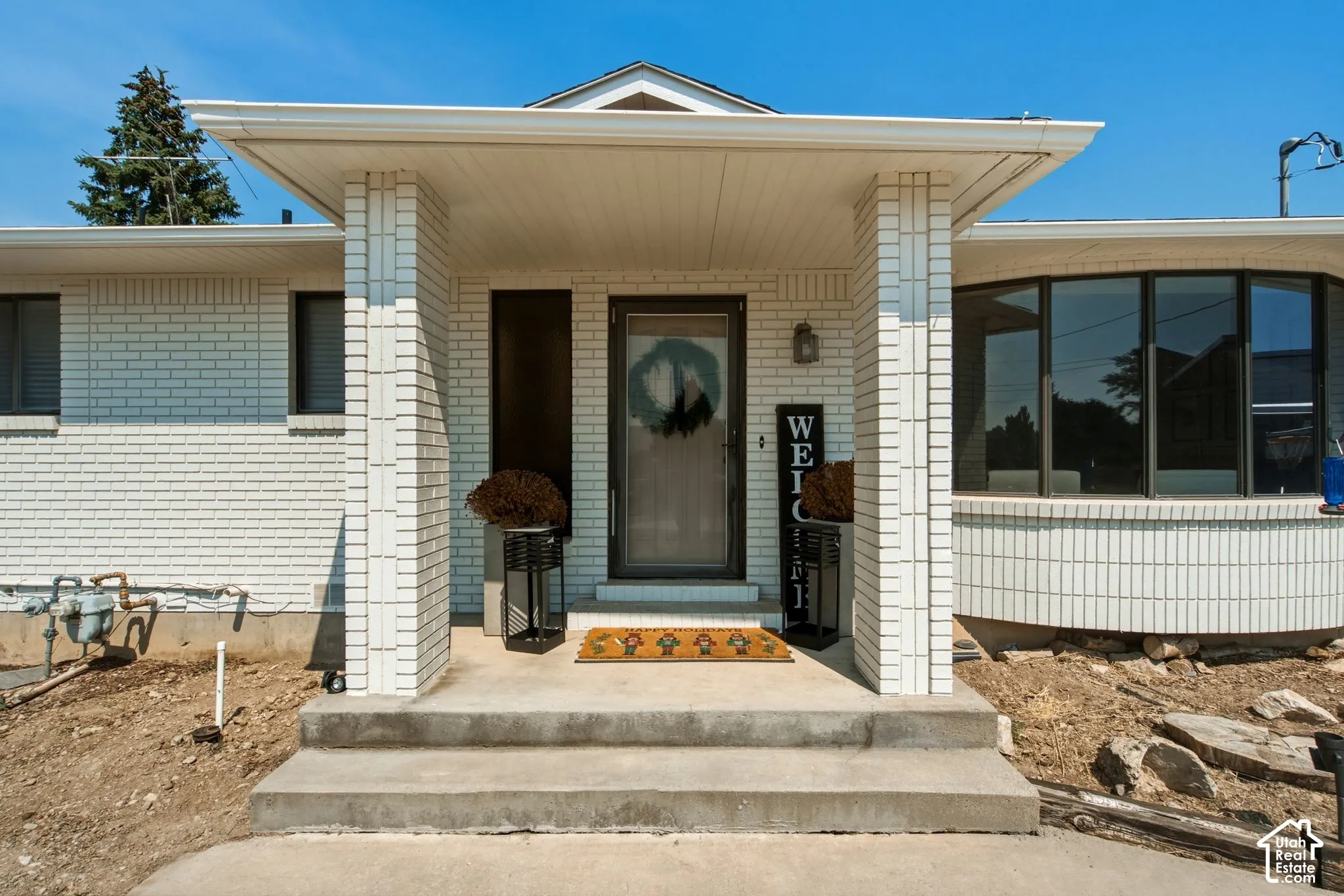 Inviting entry featuring a covered porch, concrete steps, and a glass-paneled front door