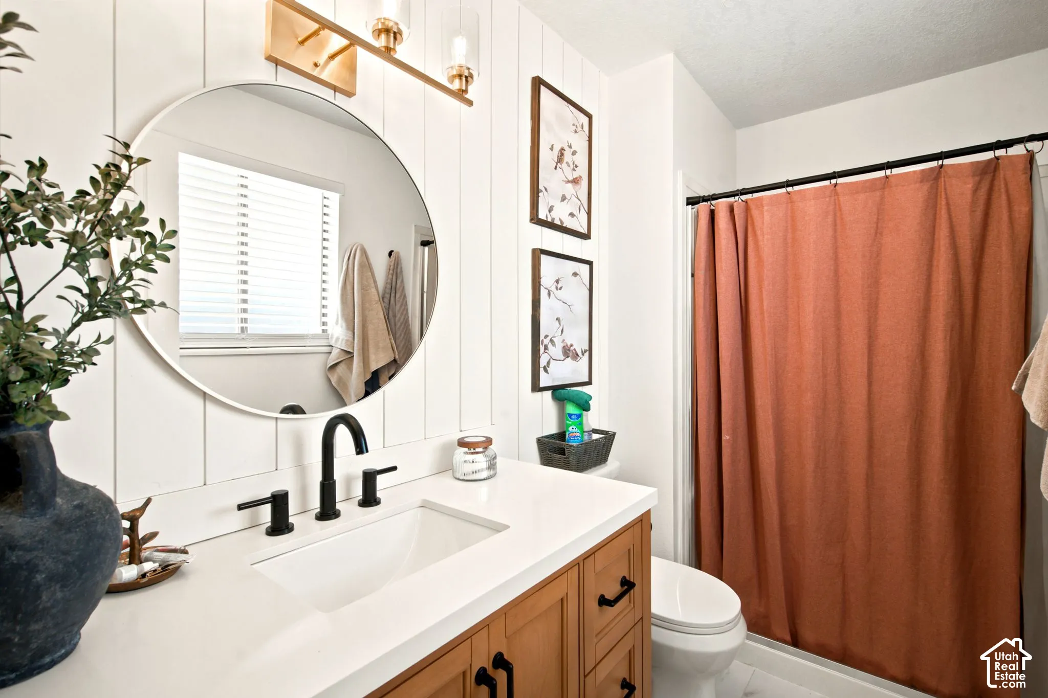 Bathroom vanity featuring a wood-finish cabinet, white countertop, and integrated rectangular sink with matte black fixtures