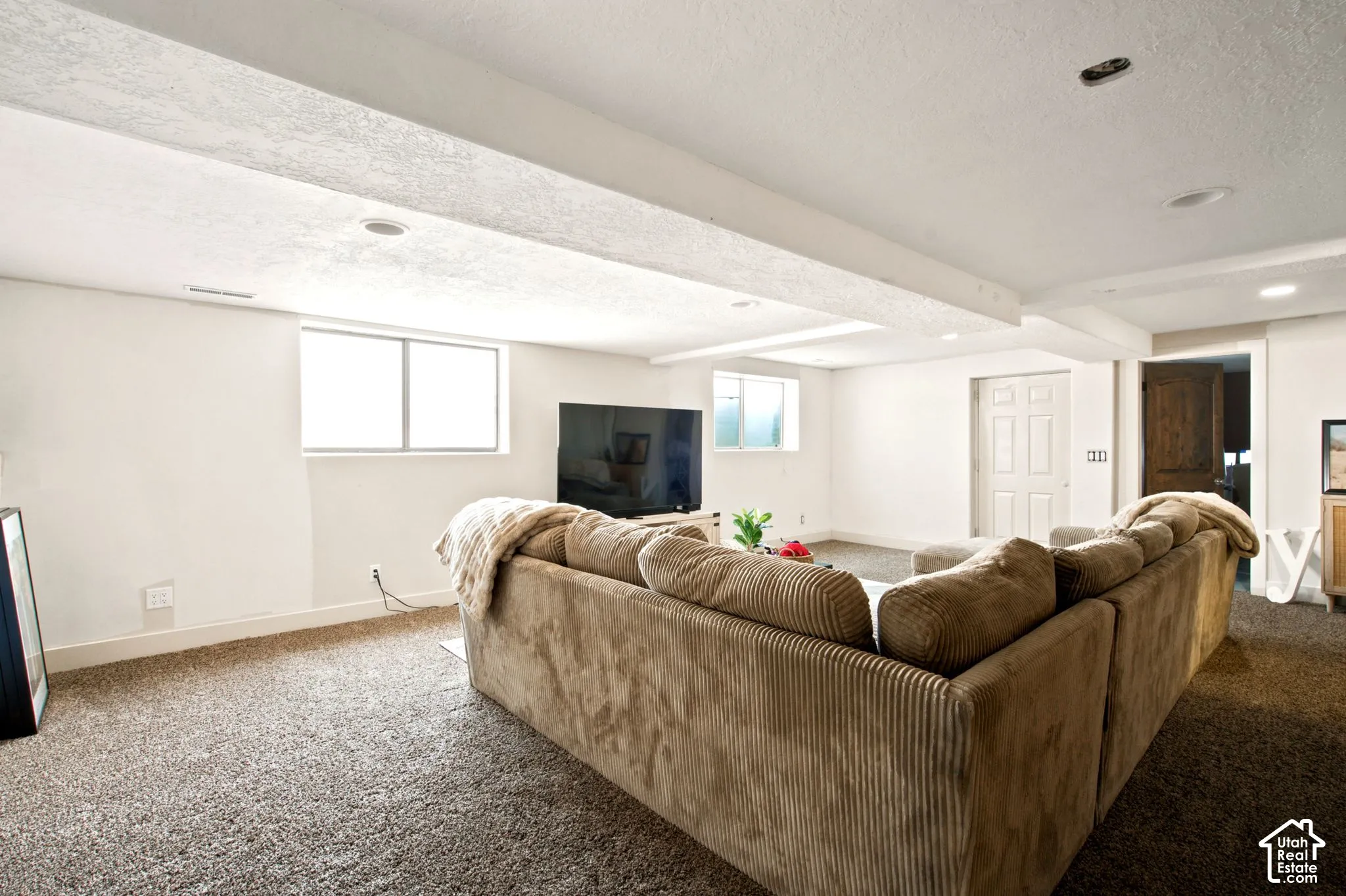 Spacious lower-level living area featuring neutral carpeting and white painted walls