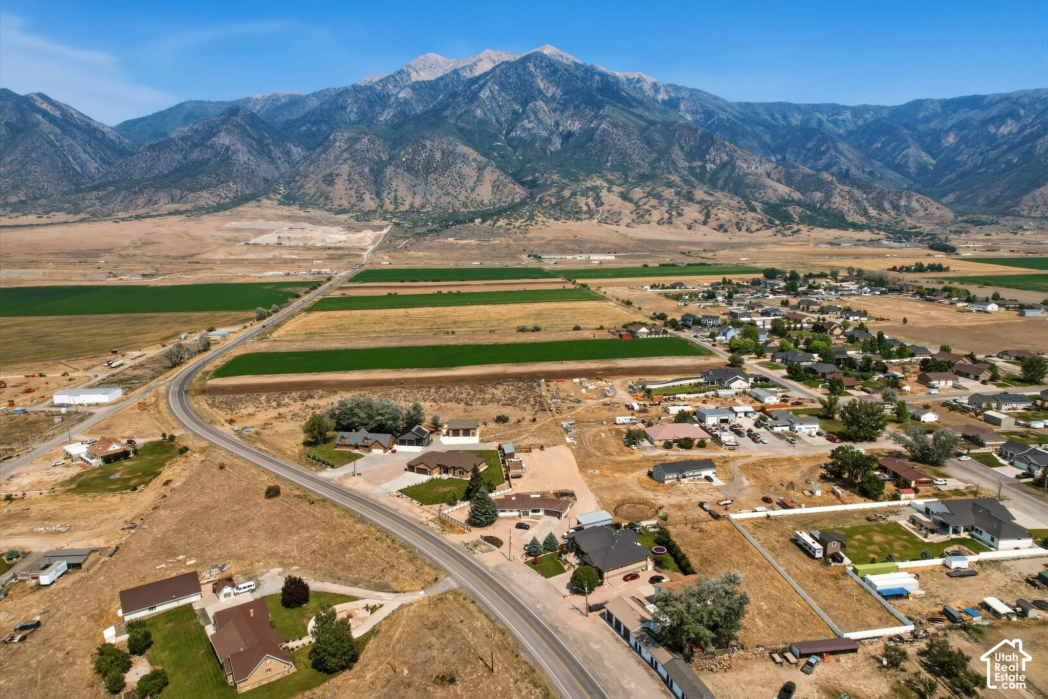 Expansive mountain range backdrop framing a rural community with agricultural fields and scattered residential properties