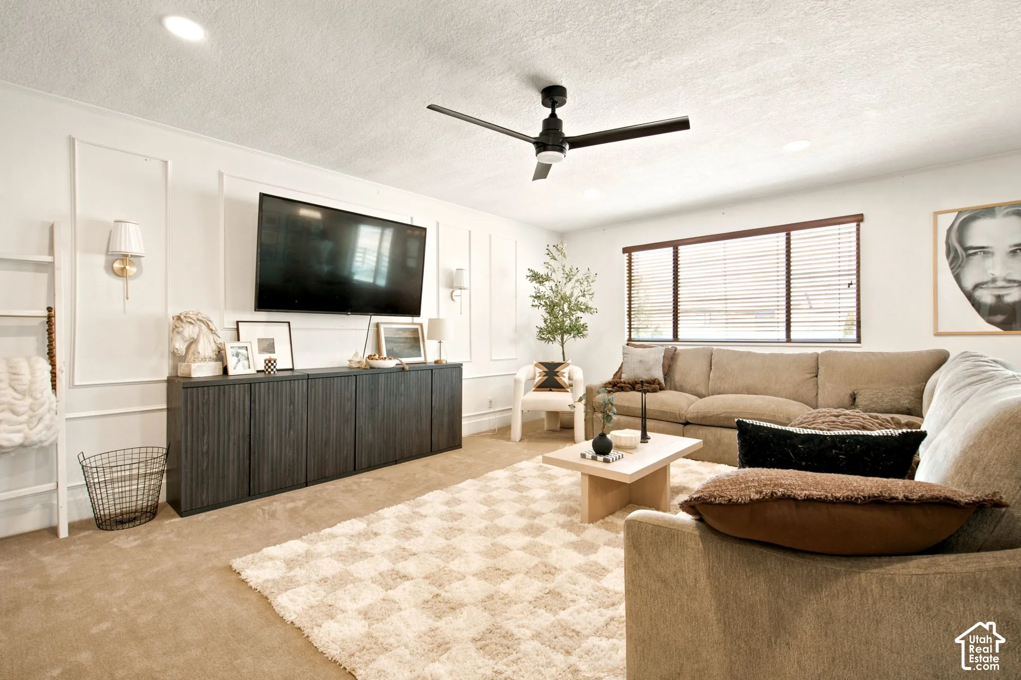 Carpeted living area featuring wainscoting, recessed lighting, and a dark-toned ceiling fan
