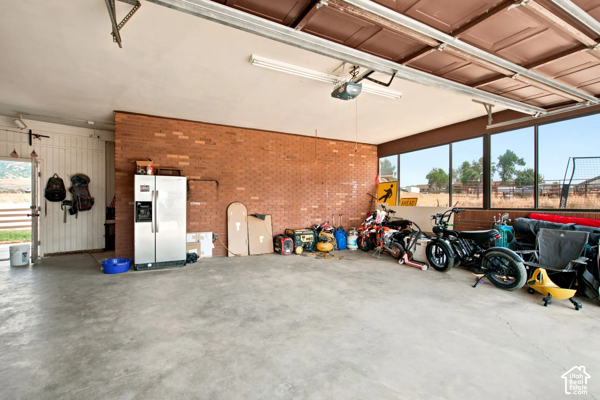 Spacious garage featuring a concrete floor, exposed brick wall, and multiple windows