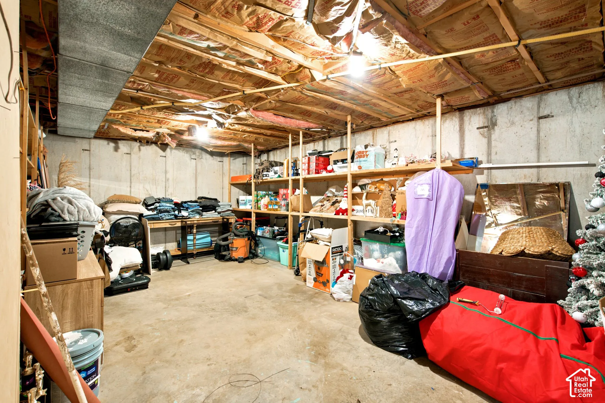 Unfinished basement featuring concrete walls, exposed joists, and overhead ductwork