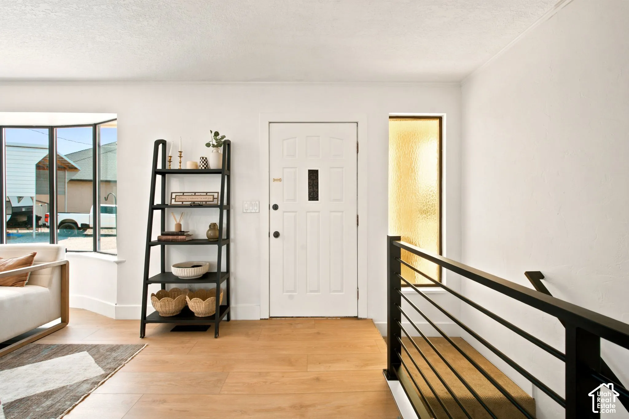 Entryway featuring light wood-finish flooring, a white paneled door with a rectangular window, and a frosted glass sidelight