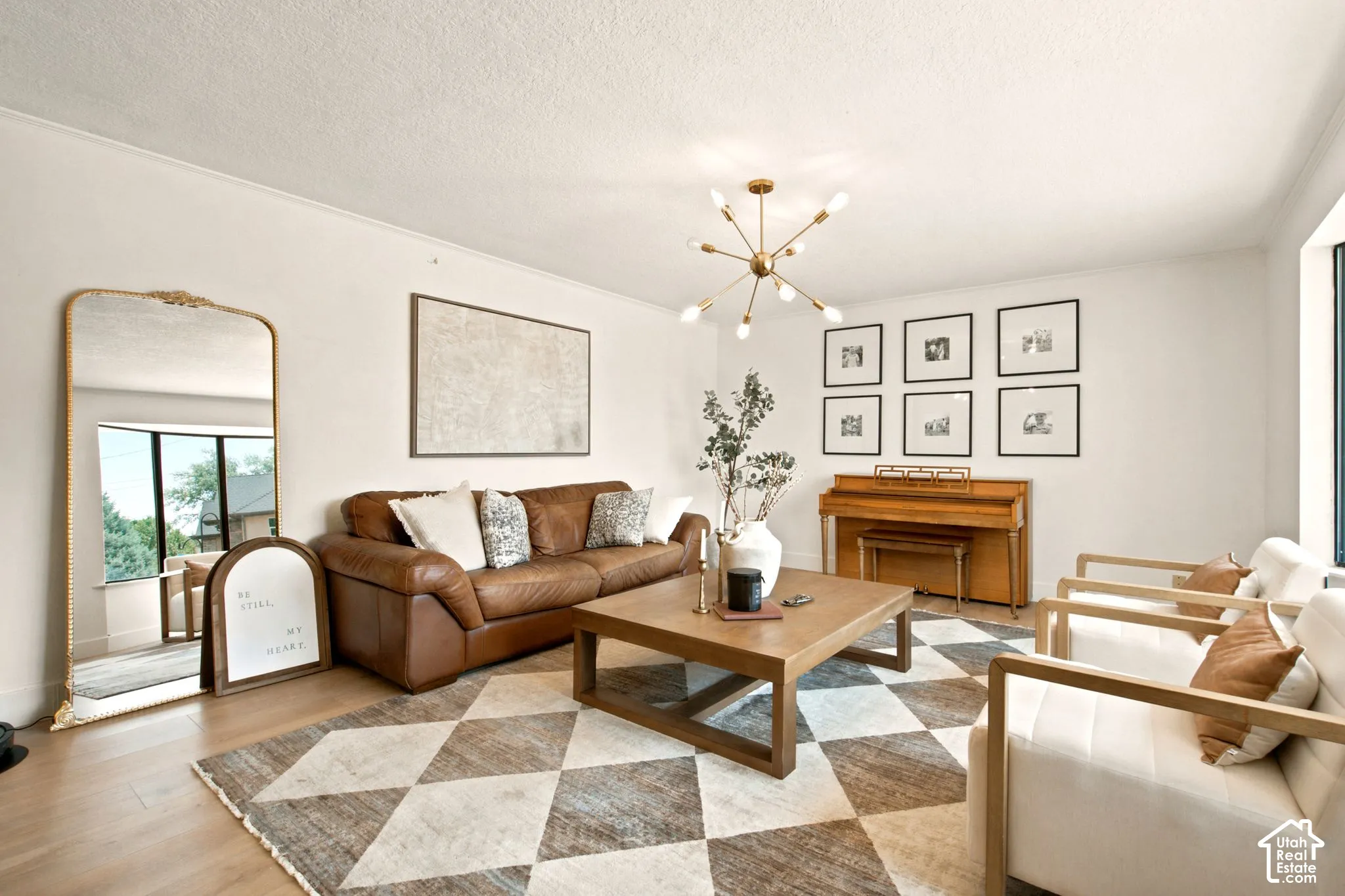 Living area featuring wood-finish flooring, a contemporary sputnik chandelier, and a large window with natural light