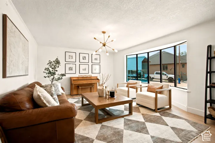 Spacious interior featuring a large bay window, light wood-finish flooring, and a modern sputnik chandelier