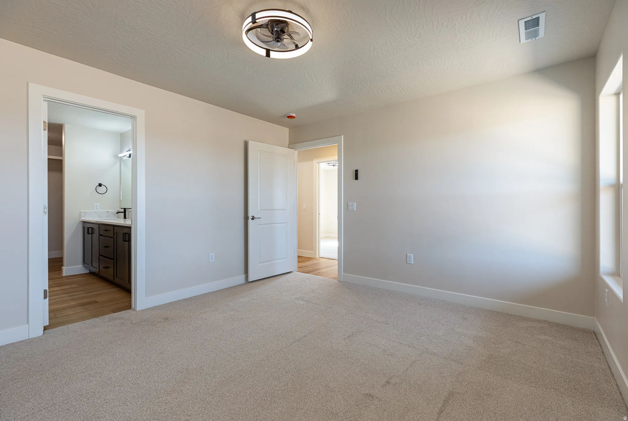 Carpeted room featuring a ceiling fan with integrated lighting, a window, and two white doors