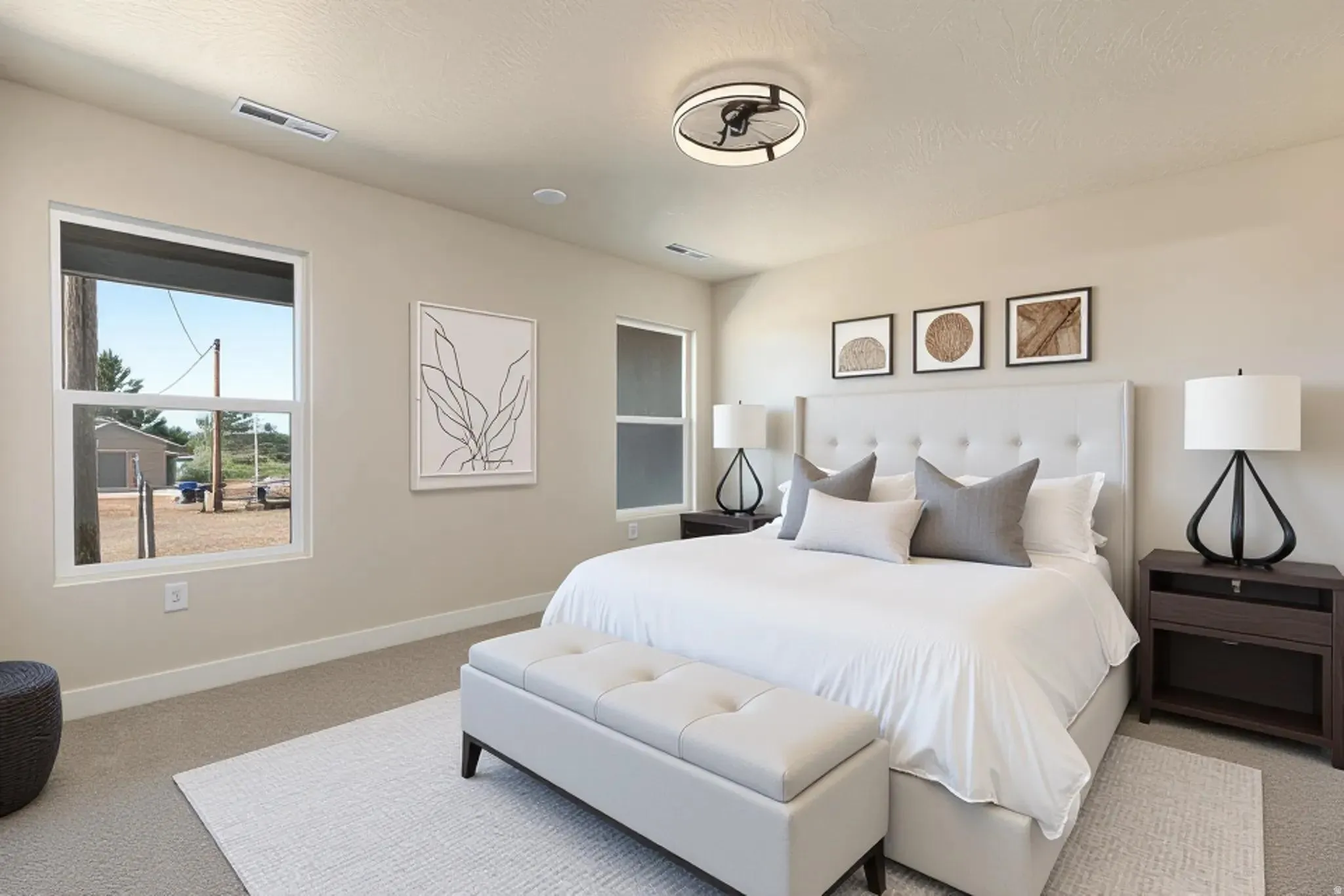 Digitally Staged-Carpeted bedroom with a built-in ceiling fan light fixture, two large windows, and neutral wall tones