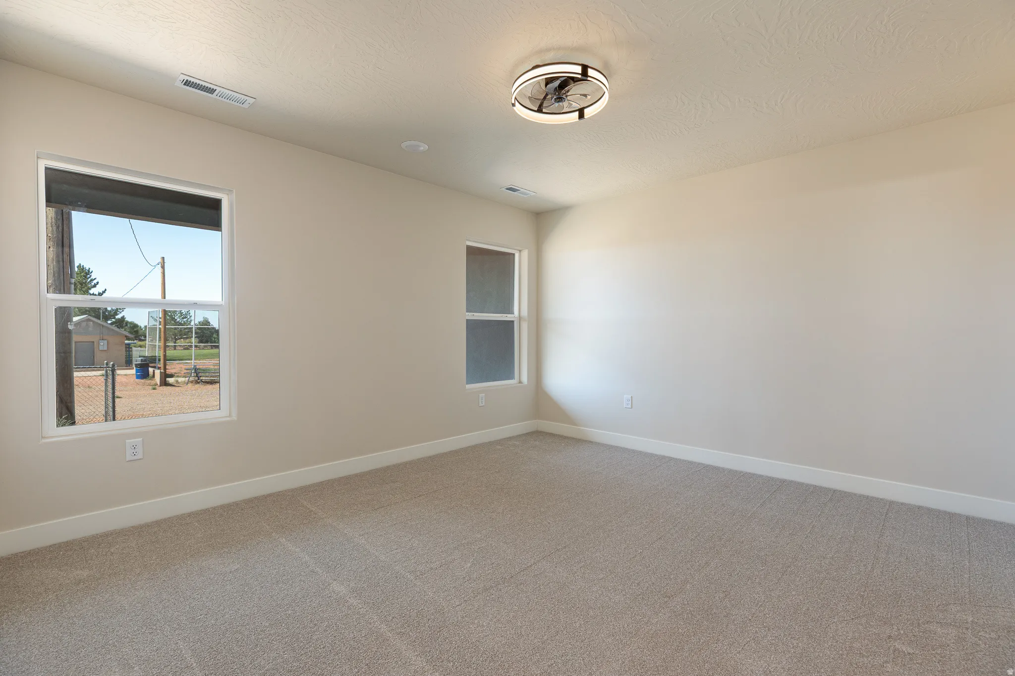 Spacious room featuring neutral wall paint, light-colored carpet, and white baseboards