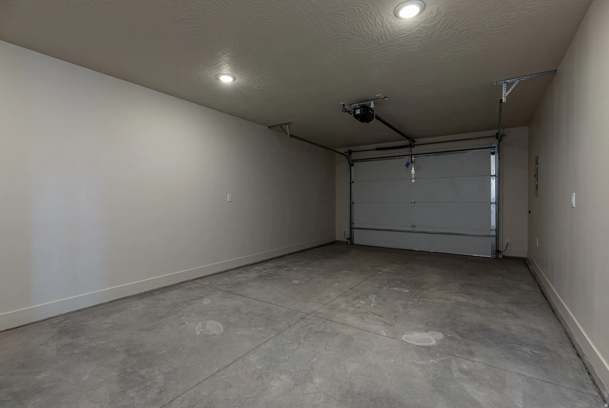 Attached garage featuring a concrete floor, light gray walls, recessed ceiling lighting, and a roll-up garage door with opener