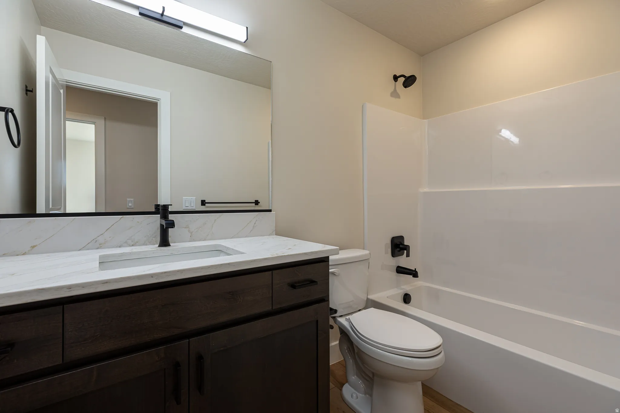 Bathroom featuring a dark wood-finish vanity with a light countertop, an integrated rectangular sink, a black faucet, and a large wall-mounted mirror